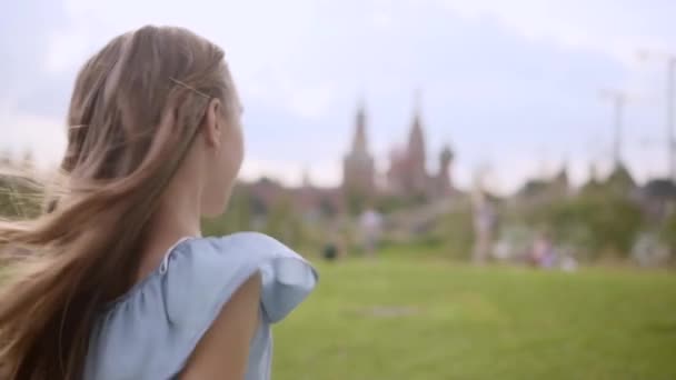 Charming long-haired girl in a blue dress spin in dance in a city park in summer — Stock Video