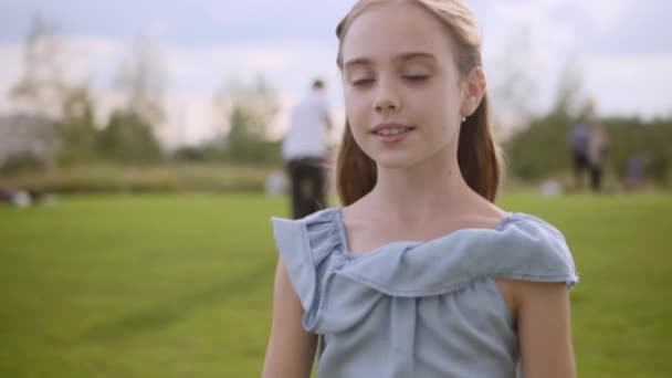 Charmant langharig meisje in een blauwe jurk spin dans in een stadspark in de zomer — Stockvideo
