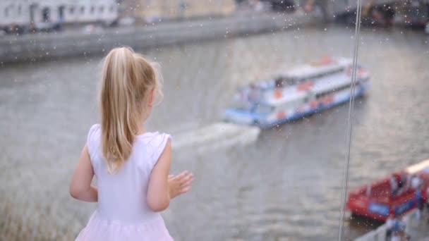 Niña en rosa mirando el río y barco a través de puente de cristal, cámara lenta — Vídeo de stock