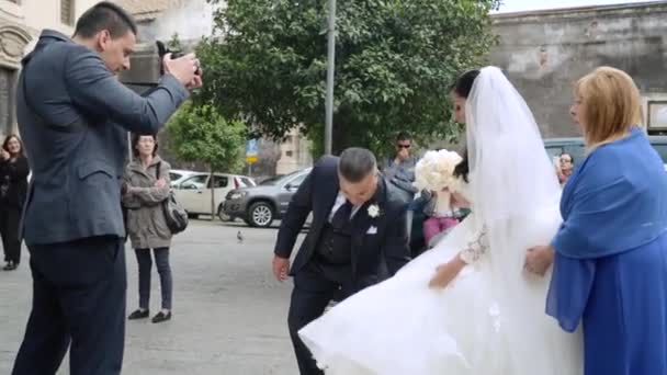 Fotografowie i operatorzy wideo robią zdjęcia panny młodej przychodzącej do kościoła — Wideo stockowe