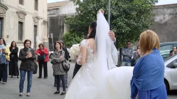 Apa fátylat borít a gyönyörű lány arcára. Menyasszony jön a templomba — Stock videók