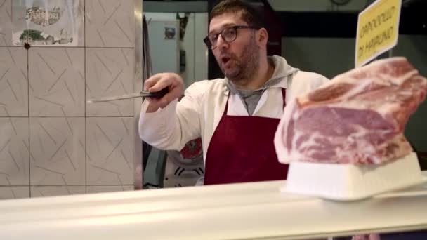 Mészáros. A hentes vékony szeletekre vágja a húst. Áruk választéka a pulton — Stock videók
