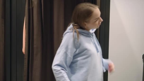 Vacker kvinna försöker på en blå tröja snurrar framför en spegel, shopping — Stockvideo