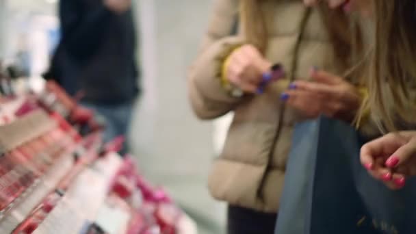 Mooie jonge vrouwen proberen nieuwe lippenstift kleur op haar hand in een cosmetica afdeling — Stockvideo