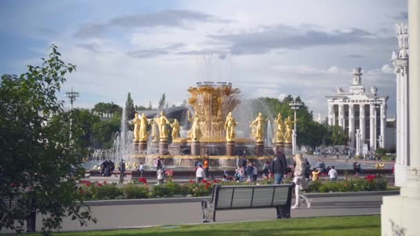 Orang-orang beristirahat di dekat Fountain Friendship of Nations yang direnovasi emas di VDNH — Stok Video