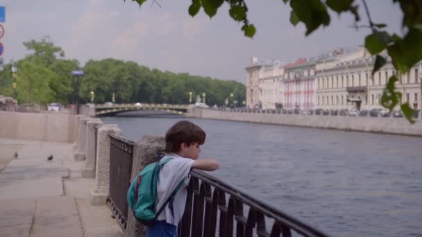Yakışıklı çocuk ellerini Fontanka Nehri 'nin metal çitlerine dayayıp şehre hayran. — Stok video