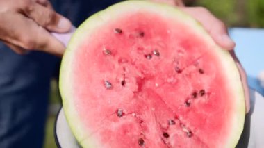 Adam olgun, sulu, lezzetli karpuz dilimler, açık havada