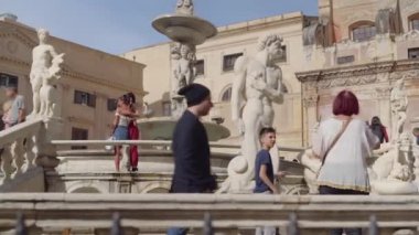 Praetorian çeşmesinin yakınındaki turistler batan güneş tarafından aydınlatılıyor