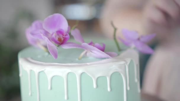 Suikerbakker versiert netjes turquoise bruidstaart met roze orchidee — Stockvideo