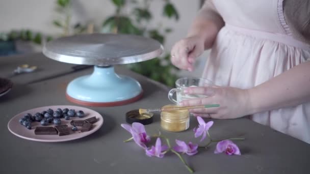 Confiseur préparer glaçure blanche pour décorer le gâteau. Or, baies, fleurs — Video