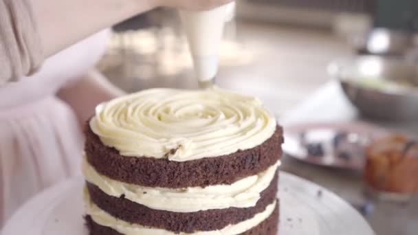 Ζαχαροπλάστης βάζει σε ένα σφουγγάρι σοκολάτας στρώμα κέικ σε μια εσωτερική στρώση κρέμας — Αρχείο Βίντεο
