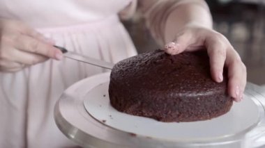 Şef çikolatalı kekin pürüzsüz kabuğunu almak için bisküvinin üstünü kesiyor.