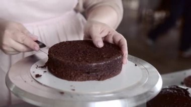 Şef çikolatalı kekin pürüzsüz kabuğunu almak için bisküvinin üstünü kesiyor.