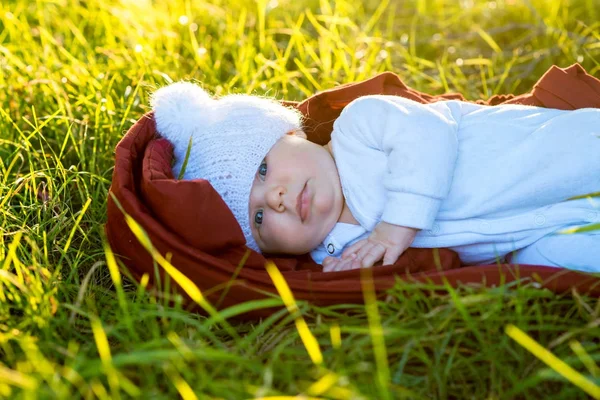 La niña pequeña con un sombrero blanco y ropa blanca acostada sobre hierba verde — Foto de Stock