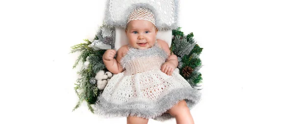 Niña acostada en la corona de Navidad en un vestido de punto blanco y tocado —  Fotos de Stock