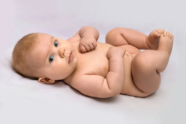 Smilling dítě leží na fialové prostěradlo v ložnici, 4 měsíce Stock Snímky