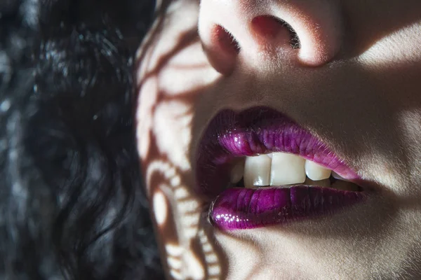 dudakları ile mor ruj ve siyah saç closeup gölge ışık ile