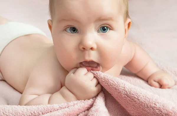 Un niño pequeño acostado en la cama y sosteniendo una manta rosa — Foto de Stock