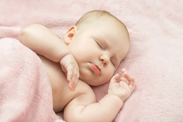 Malé dítě spí v posteli pod dekou růžové — Stock fotografie