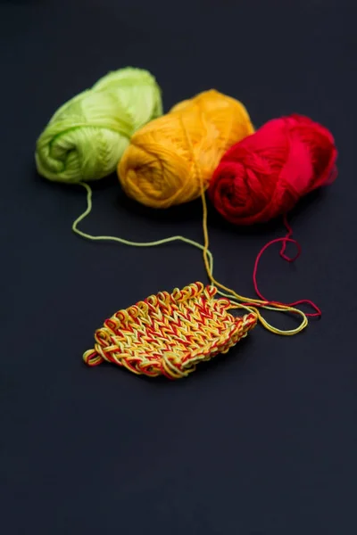 topları iplik kırmızı yeşil ve sarı siyah bir arka plan ve örgü iğneleri dikey