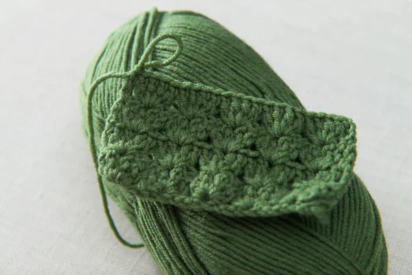 Exemplo de tricô, fio verde com crochê em um fundo bege — Fotografia de Stock