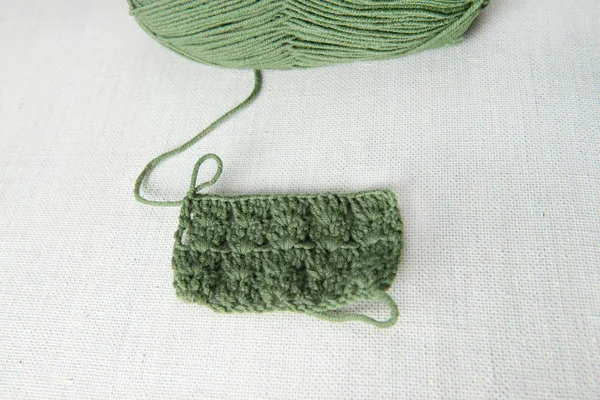 Örgü, tığ işi bej renkli arka plan üzerinde ile yeşil iplik örnek