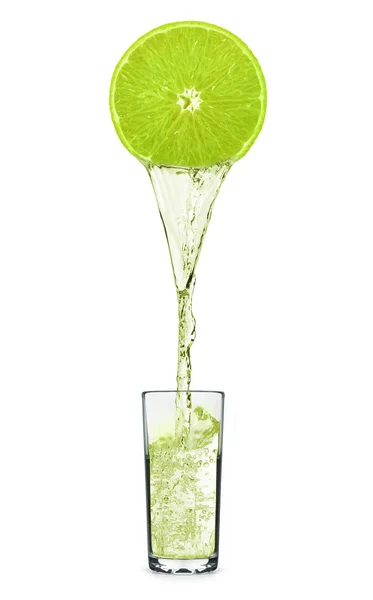 Suco que despeja de fruta de lima em vidro isolado em branco — Fotografia de Stock