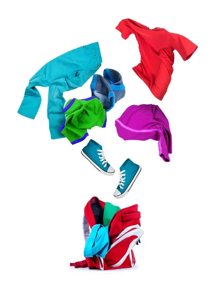 Vêtements colorés tombe dans un sac à dos isolé sur backgr blanc — Photo
