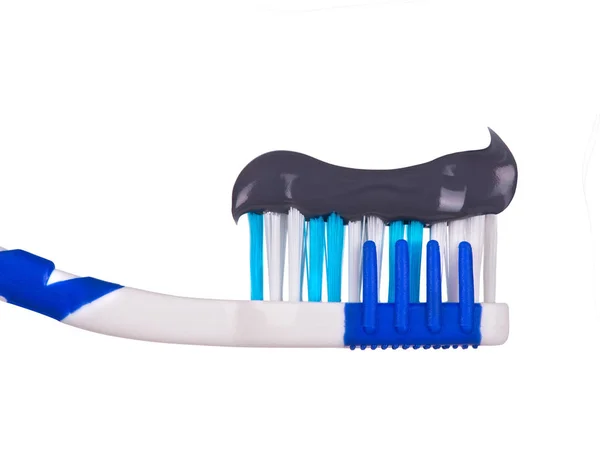 Темная зубная паста на зубной щётке крупным планом, изолированная на белом — стоковое фото