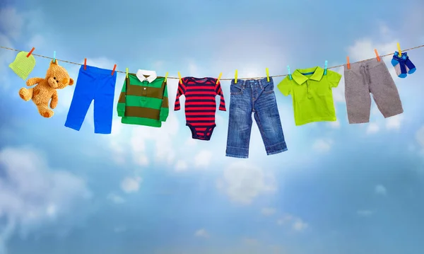 Multicolored clothes on clothesline against blue sky — Stock Photo, Image