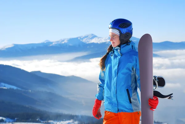 Dívka stojící na vrcholu hory s snowboard v rukou — Stock fotografie