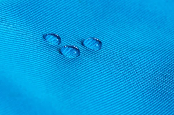 Blå vattentät tyg med vattendroppar på nära håll — Stockfoto