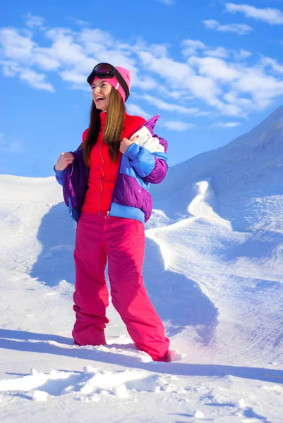 Menina feliz remove jaqueta de esqui, de pé em cima de uma montanha de neve — Fotografia de Stock