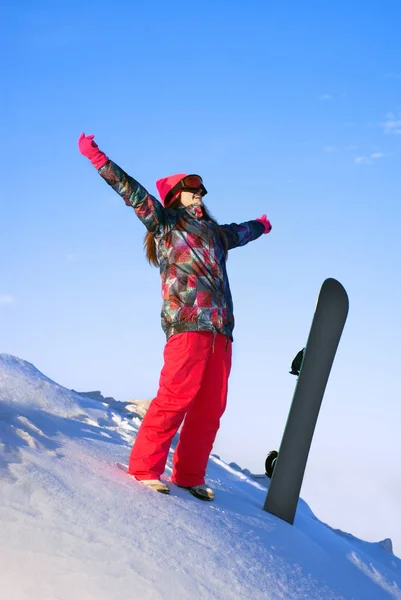 Glückliches Mädchen steht mit Snowboard auf einem Berggipfel — Stockfoto