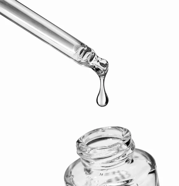 Druppel valt van een precisiepipet in een cosmetische fles op wit — Stockfoto