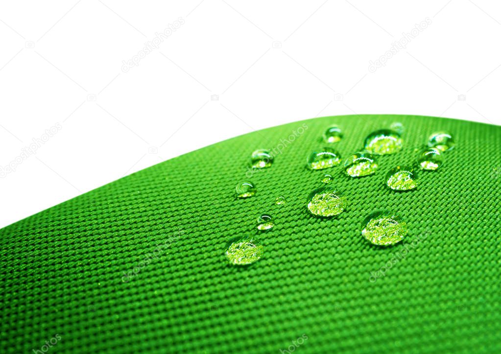 Green waterproof fabric with waterdrops close up on white 