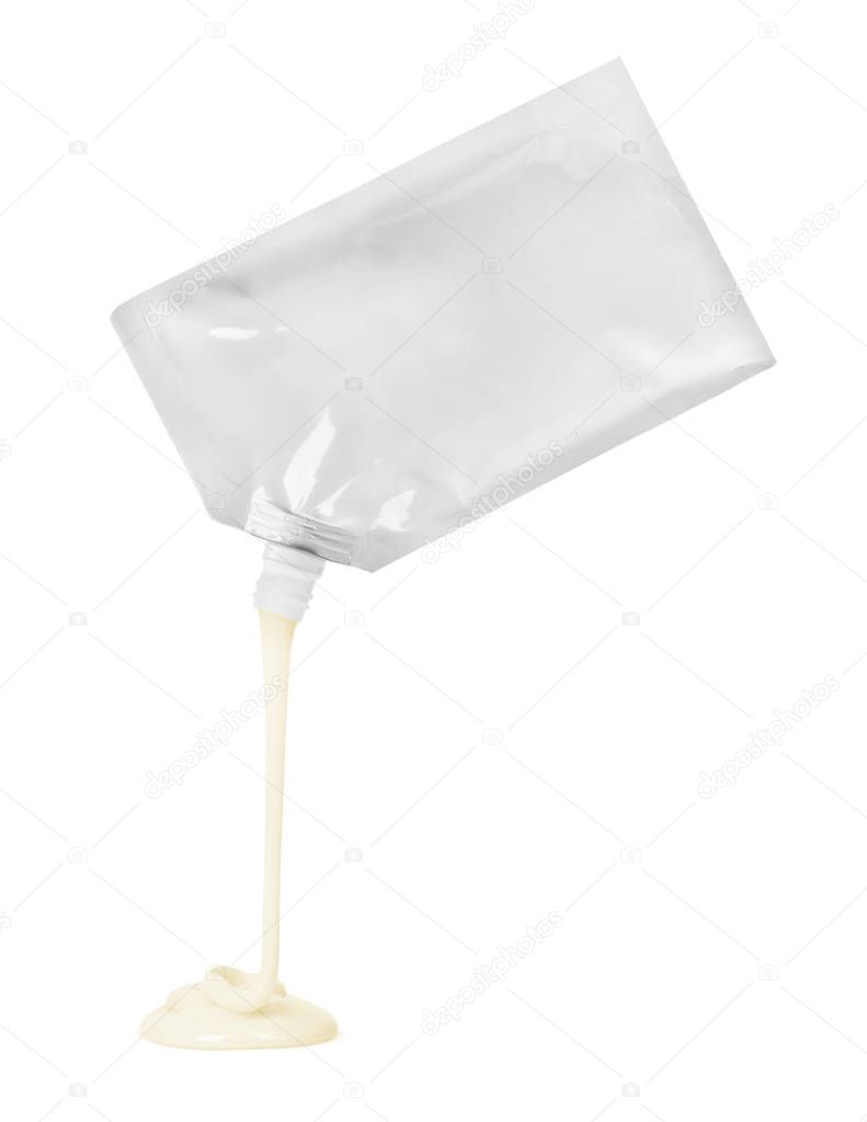 Mayonnaise flows out of the package on white background