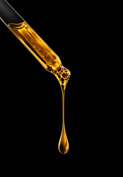 Siyah arka plan üzerine yağlı damla closeup ile kozmetik pipet