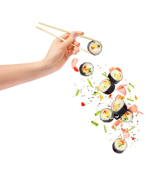 Pedaços de sushi e sushi caem com pauzinhos de madeira na mão feminina — Fotografia de Stock