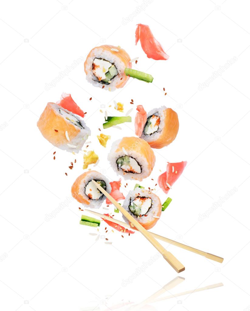 Pieces of fresh sushi with chopsticks frozen in the air on white