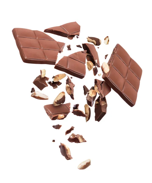 Chocolate bar with nuts broken into pieces in the air, isolated on a white background