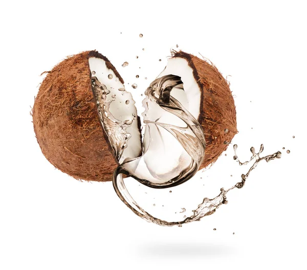 Сок выплескивается из кокосовой половинки на белом фоне — стоковое фото