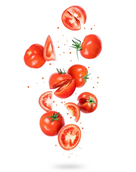 Celá a nakrájená čerstvá rajčata ve vzduchu, izolovaná na bílém pozadí — Stock fotografie