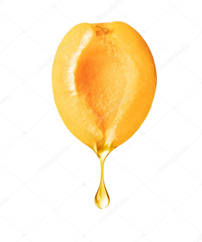 A drop dripping from a half of apricot isolated on white background 