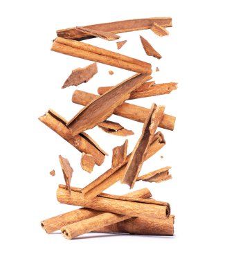 Tarçın çubukları beyaz arka planda bir yığın üzerine düşüyor.