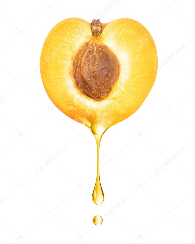 A drop dripping from a half of apricot close up on a white background