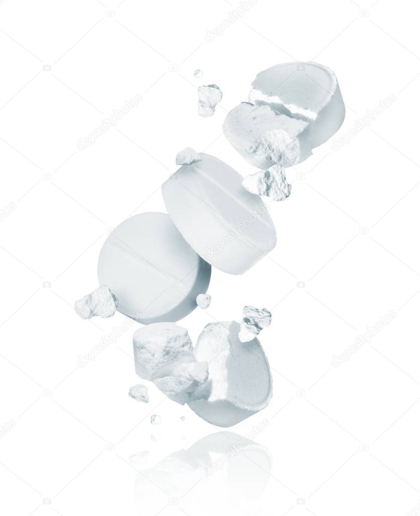 Crushed and whole pills are falling down on a white background