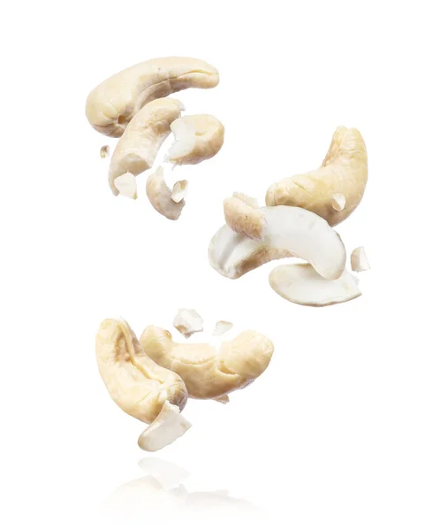 白い背景に空気中の粉砕カシューナッツのグループ — ストック写真