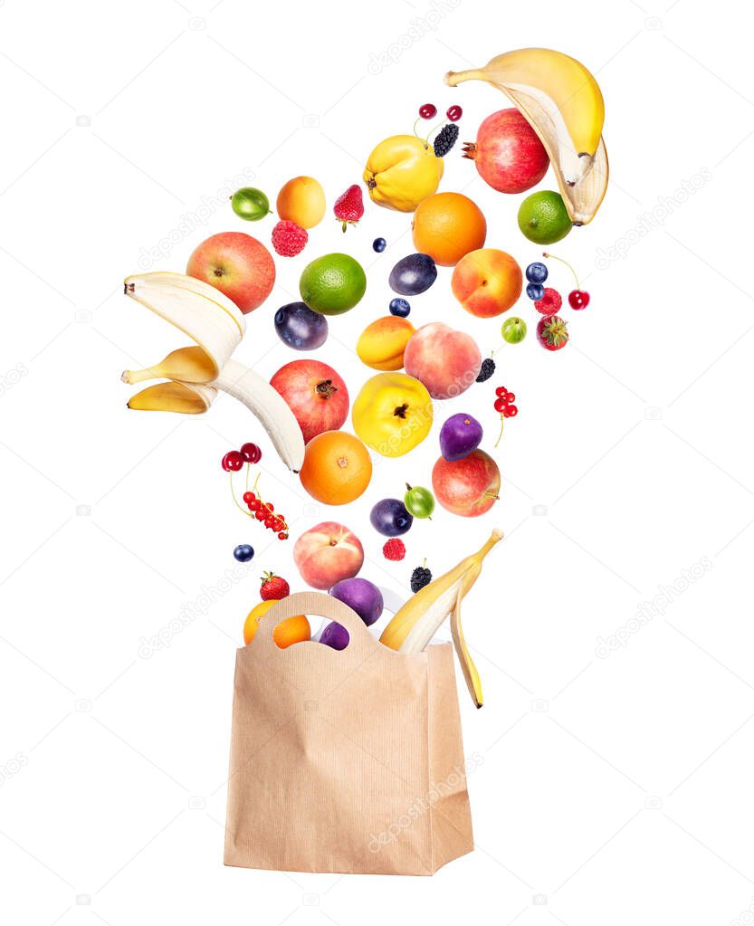 Various fruits and berries fly out from a grocery paper bag, isolated on white background