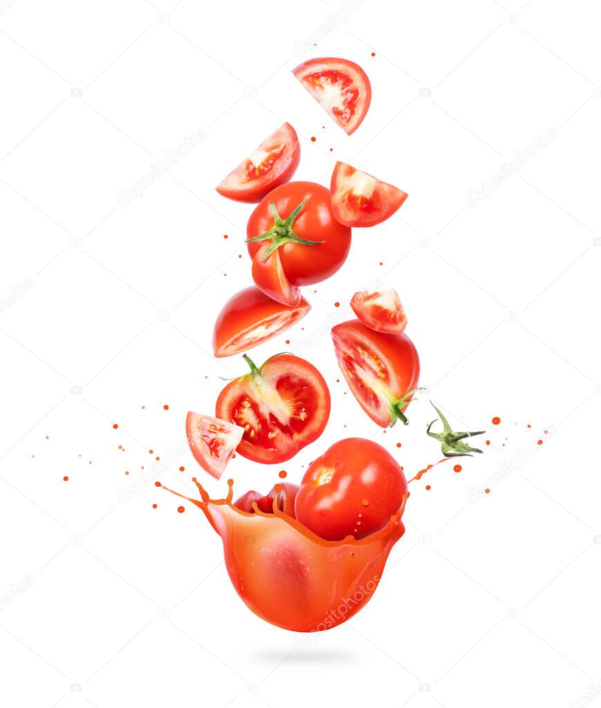 Whole and sliced fresh tomatoes are falling in splashes of juice on a white background
